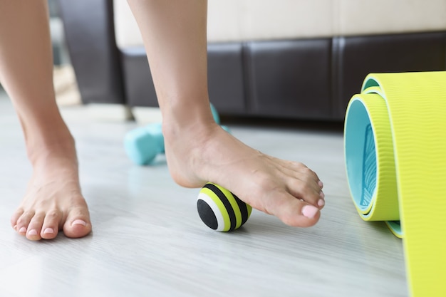 여성 다리는 집 근접 촬영에서 바닥에 작은 스포츠 공을 굴립니다