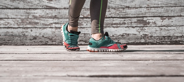 женские ножки в колготках и спортивной обуви на деревянном фоне, концептуальный спорт