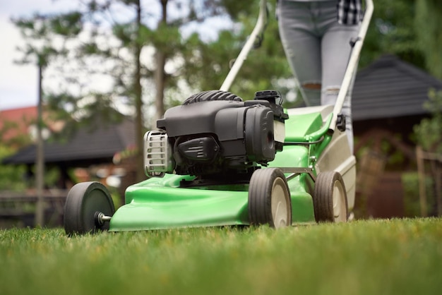 Female legs of woman using lawn mower