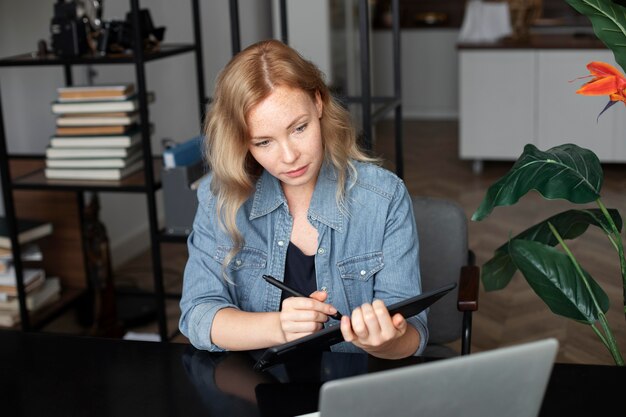 グラフィックタブレットで彼女のオフィスで働く女性のロゴデザイナー