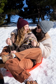 겨울 여행 중 썰매를 타고 웃는 여성 연인들
