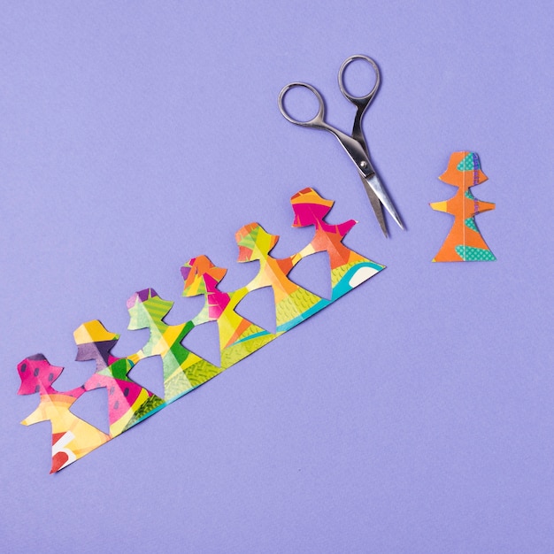 Female made from colourful paper being cut by scissors