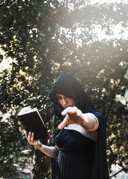 Female magician practising witchcraft in sunlit forest