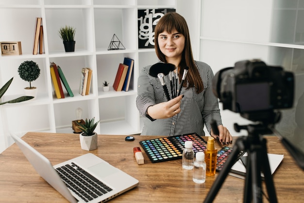 Blogger di trucco femminile con streaming con fotocamera e laptop