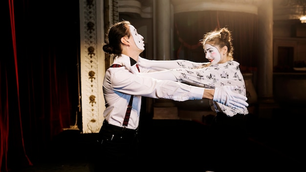 Female and male mime artist trying to hug each other on stage