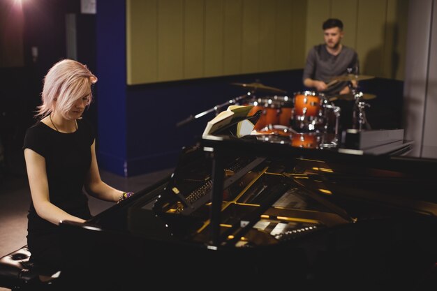 Female and male students playing piano and drum set