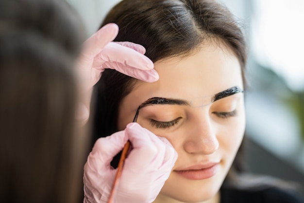 Female master make contours of eyebrows for pretty young model