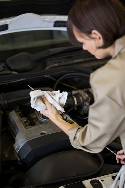 Женский механик проверять уровень масла в двигателе автомобиля