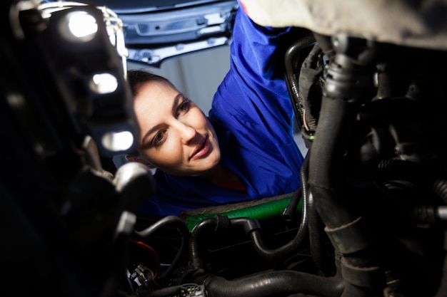 女性整備士が車のエンジンを調べます