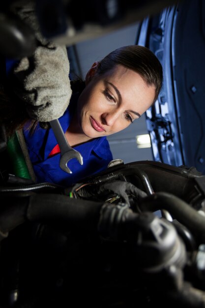 Female mechanic examining car engine