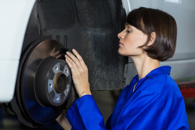 Female mechanic examining a car wheel disc brake