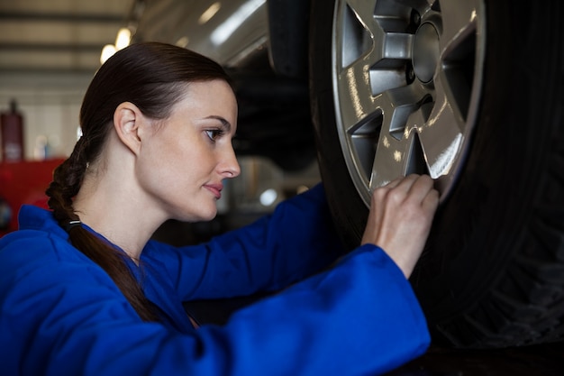 車のホイールを調べる女性メカニック