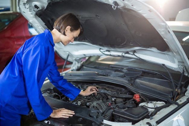 Female mechanic examining a car