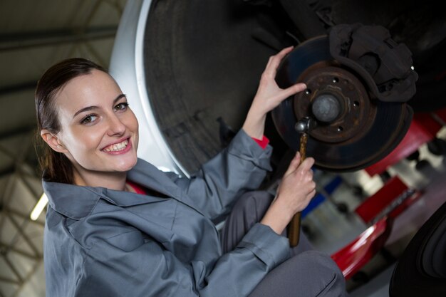 Female mechanic fixing car brake