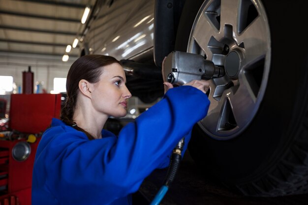 Female mechanic fixing a car wheel