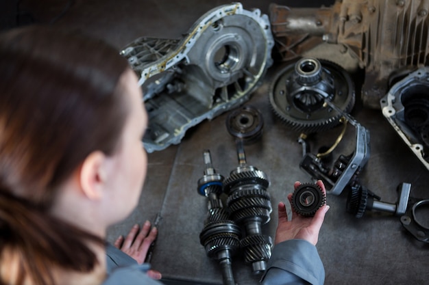 Female mechanic holding spare parts of car