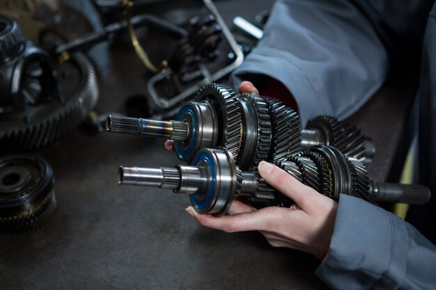 Female mechanic holding spare parts of car