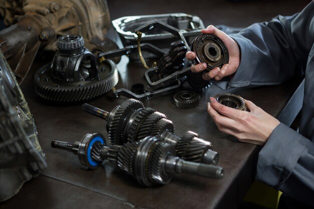 Female mechanic holding spare parts of car