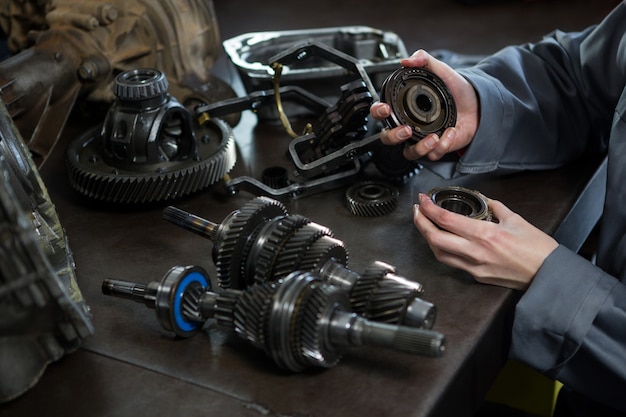 Female mechanic holding spare parts of car