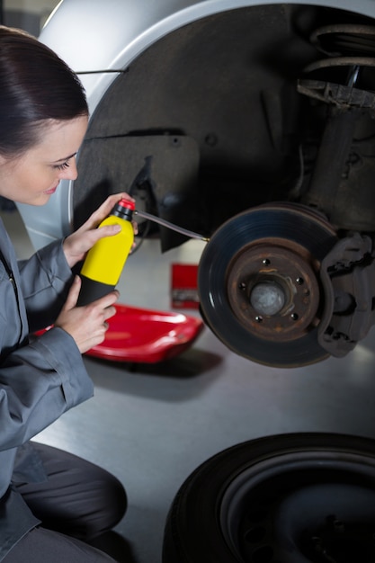 Free photo female mechanic oiling car brake