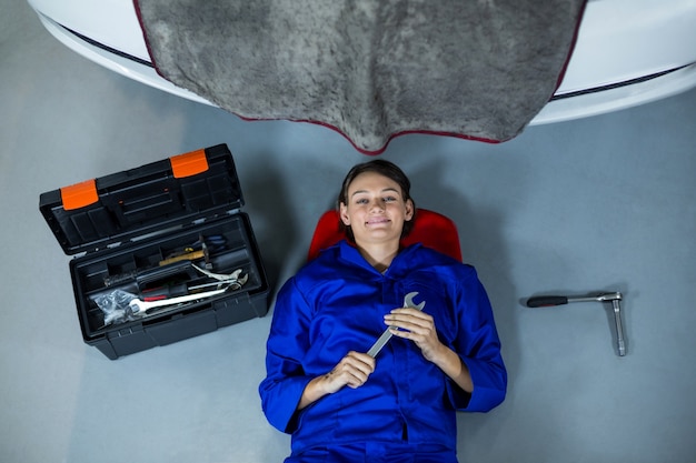 Female mechanic smiling while repairing a car