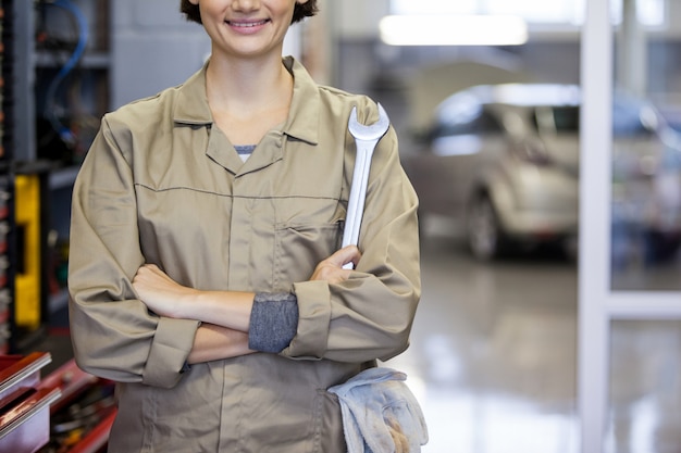 Foto gratuita meccanico femminile con le braccia incrociate e chiave