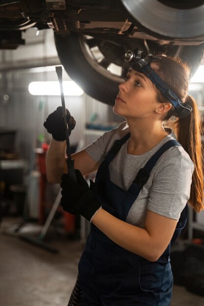 Female mechanic working on a car in the shop
