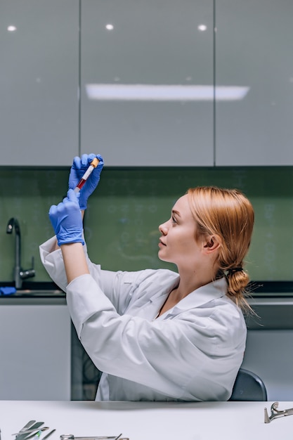 Female medical or scientific researcher looking at a test tube in a laboratory.