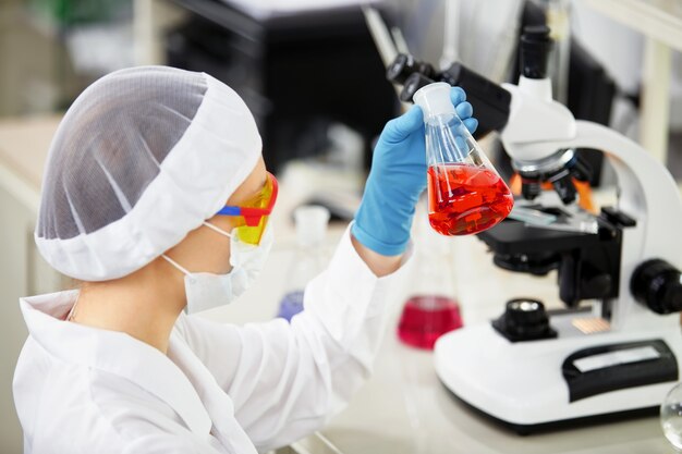 A female medical or scientific researcher or woman doctor looking at a test tube of solution