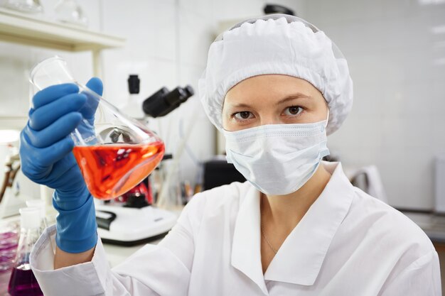 A female medical or scientific researcher or woman doctor looking at a test tube of solution