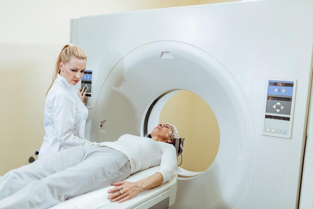 병원의 검사실에서 CT 스캔 절차 중 여성 의료 기술자 및 성숙한 환자