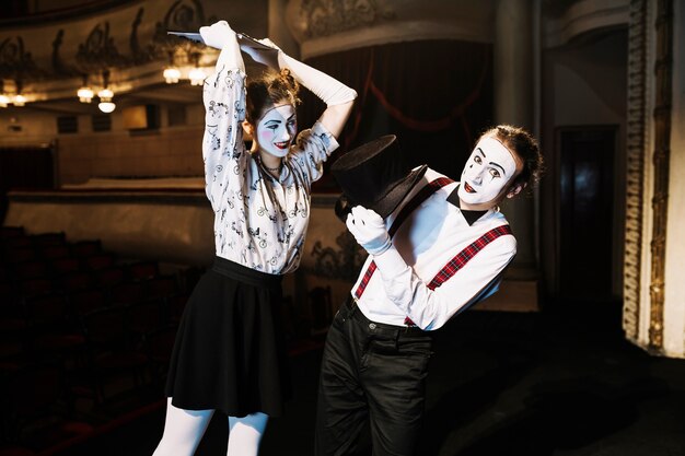 Female mime artist hitting male mime artist with script