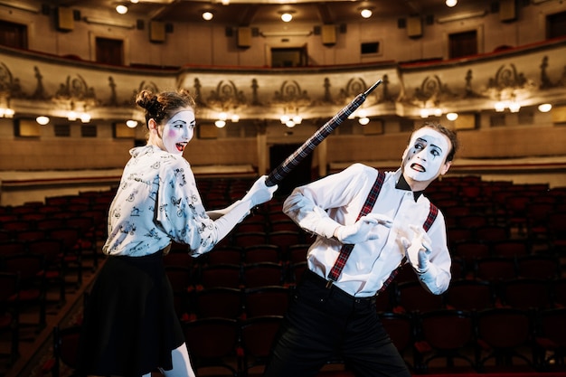 Female mime artist hitting male mime with an umbrella