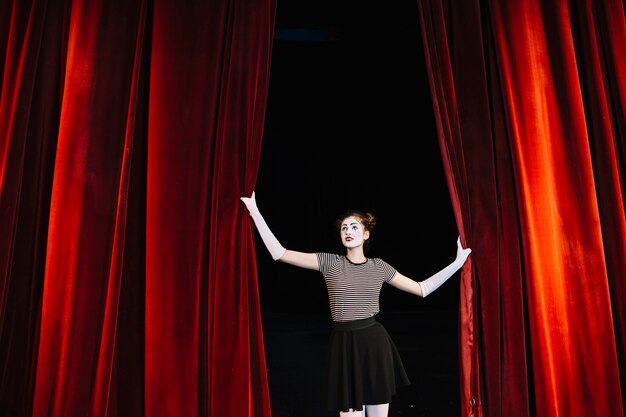 Female mime artist holding red curtain