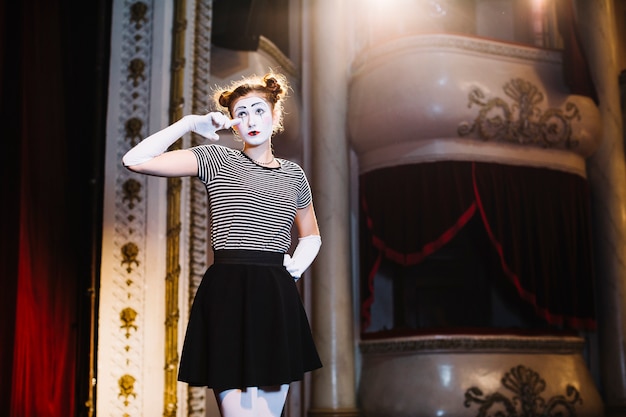 Female mime artist standing crying on stage