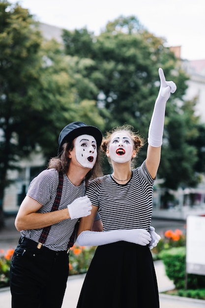 Free photo female mime pointing upwards showing something to male mime