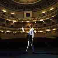 Free photo female mime reading manuscript in empty auditorium