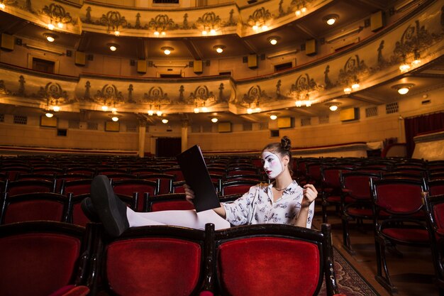 Female mime sitting on chair reading manuscript