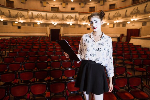 Female mime standing in an auditorium holding script on clipboard