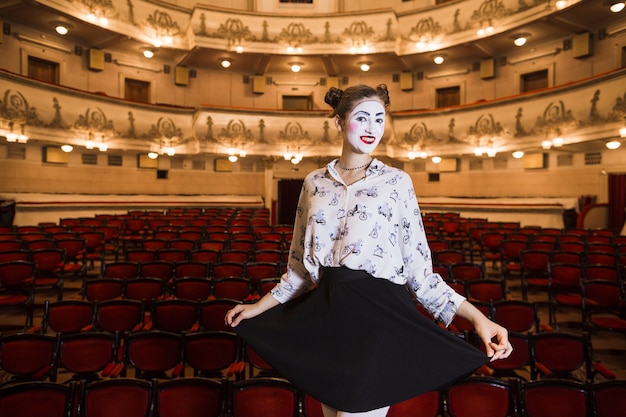 Female mime standing in an auditorium posing