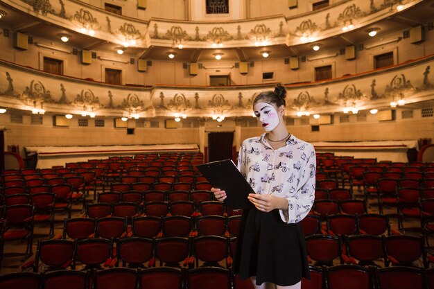 Female mime standing in auditorium reading script