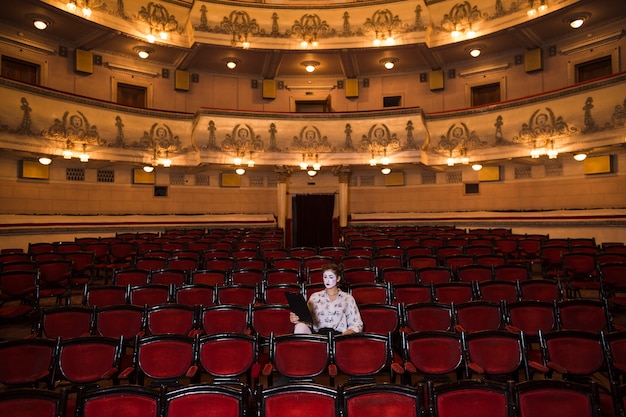 Foto gratuita mime femminile con manoscritto seduto al centro dell'auditorium