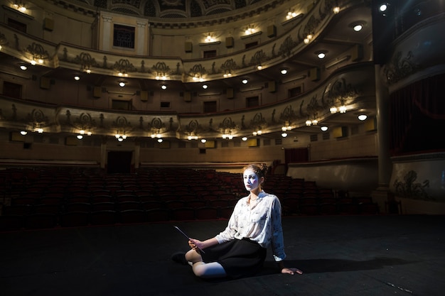 Female mime with manuscript sitting on stage