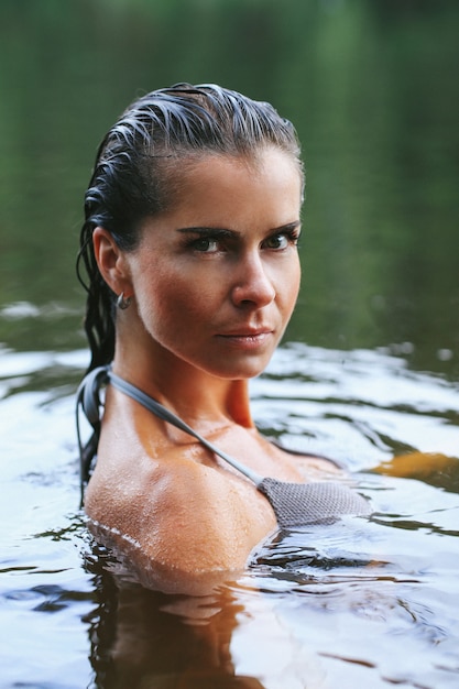 Foto gratuita modello femminile in costume da bagno nero nel lago