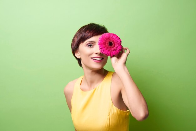 Female model covering eye with flower