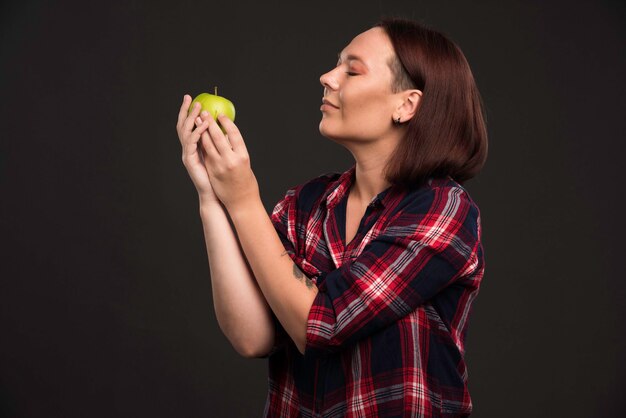 Female model in fall winter collection outfits holding a green apple and enjoying it. 