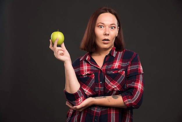 Female model in fall winter collection outfits holding a green apple and feeling surprized. 