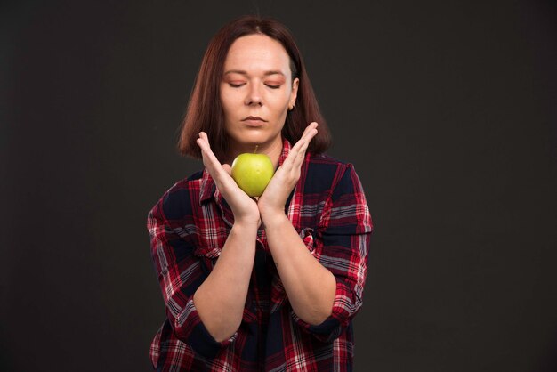 Female model in fall winter collection outfits holding a green apple under her chin. 