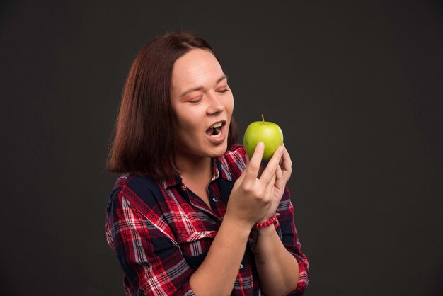 Female model in fall winter collection outfits holding a green apple and looking with appetite.