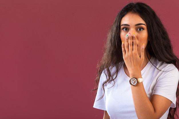 Il modello femminile fa la faccia sorpresa, vista frontale sulla parete rosa.